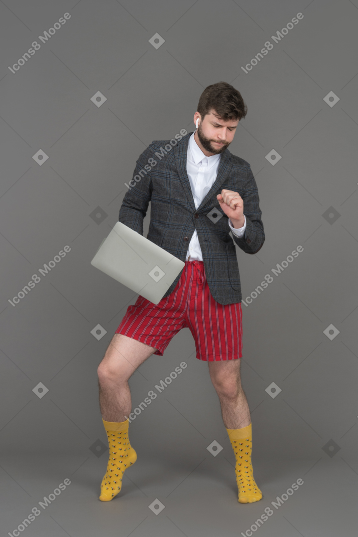 A cheerful young man dancing with a laptop