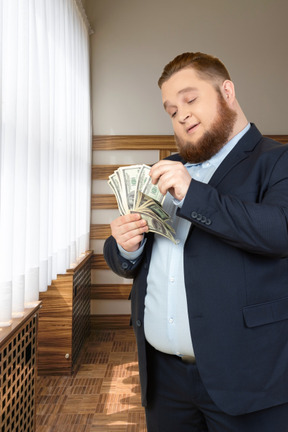 A man in a suit is holding a stack of money