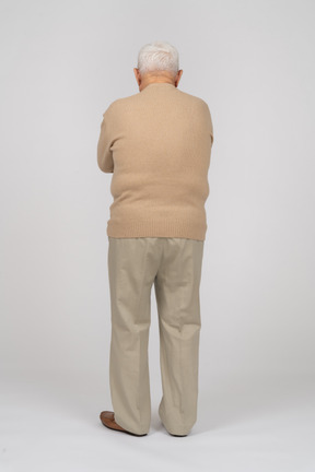 Rückansicht eines alten mannes in freizeitkleidung, der mit verschränkten armen steht