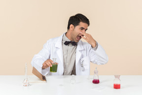 Junger männlicher wissenschaftler, der etwas schlechtes riecht, während er in einem labor arbeitet