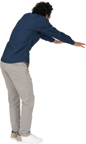 Vista posteriore di un uomo in abiti casual che si china con le braccia tese
