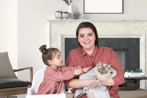 Mother holding a cat and daughter wants to pet it