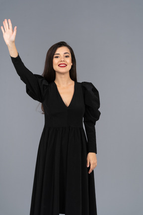 Front view of a smiling greeting young lady in a black dress