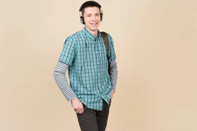 Estudiante sonriente de pie con una mochila y auriculares