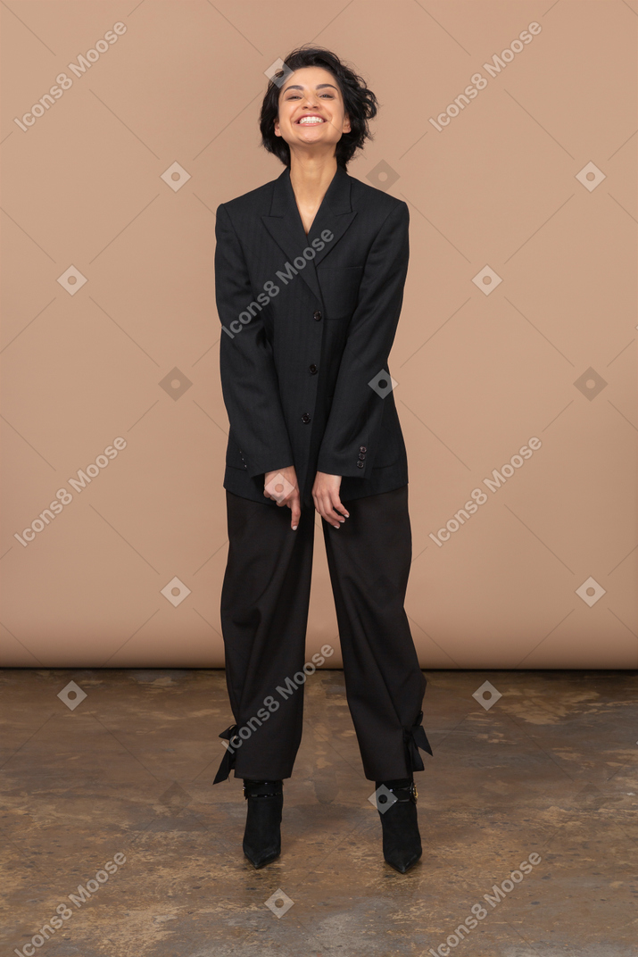 Vorderansicht einer glücklichen geschäftsfrau in einem schwarzen anzug, der kamera betrachtet
