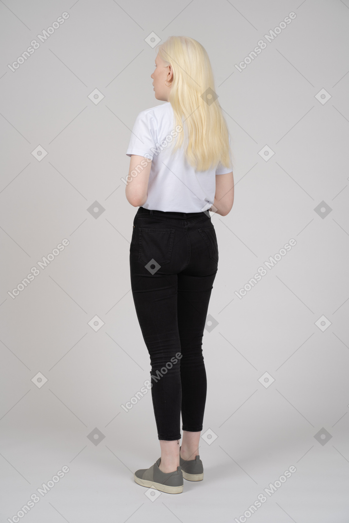 Dreiviertel-rückansicht einer jungen blonden frau in freizeitkleidung