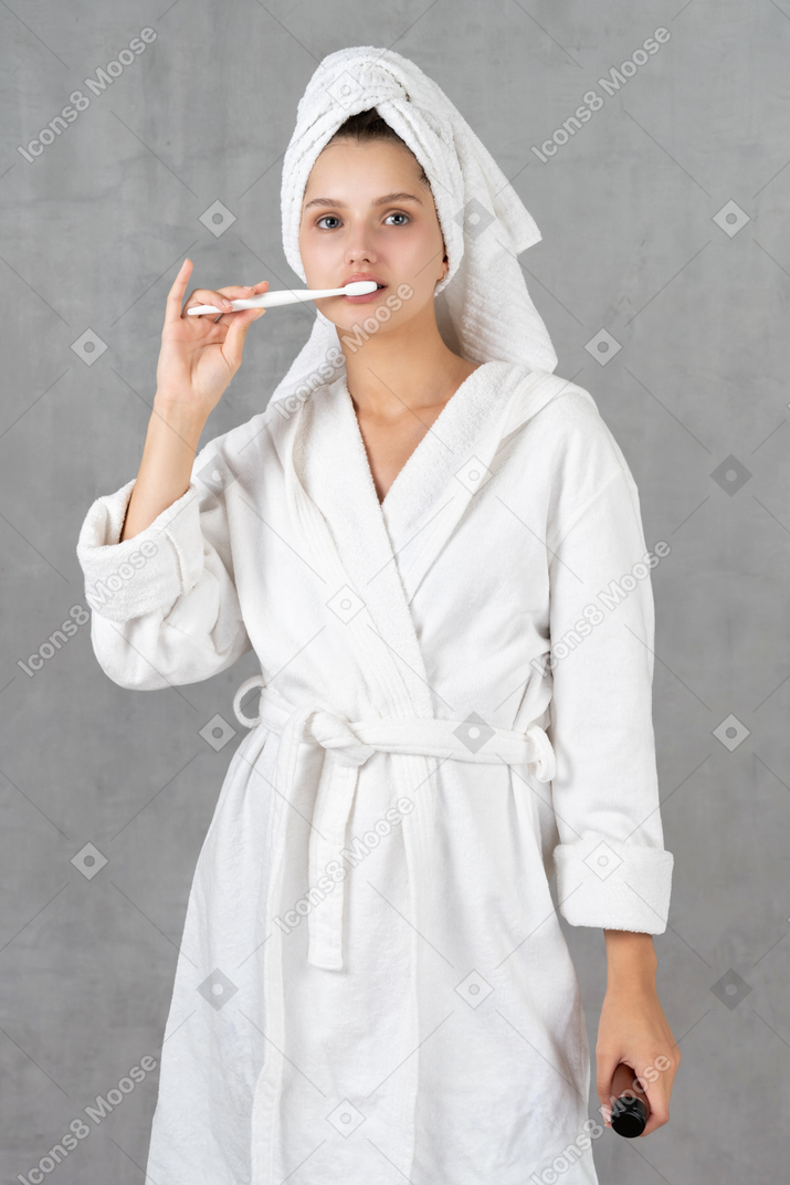 Mujer en bata de baño cepillándose los dientes