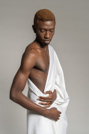 Вид сбоку на молодого человека в белом полотенце