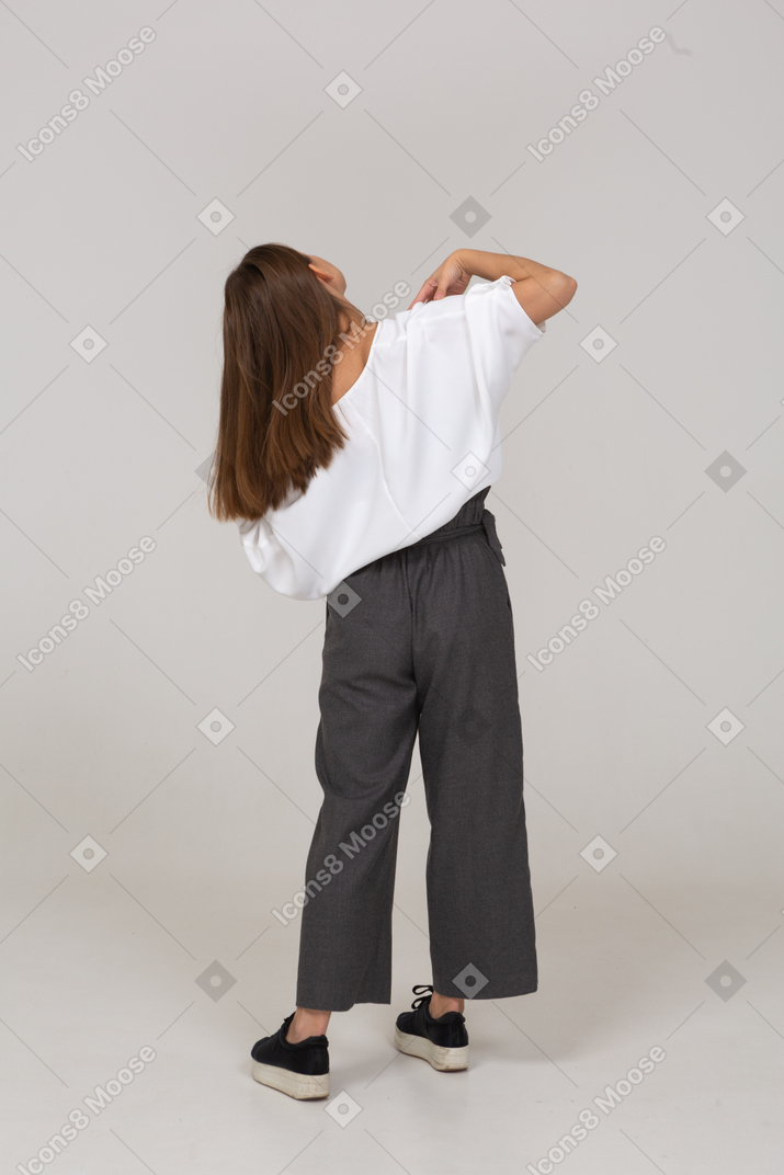 Back view of a young lady in office clothing touching her shoulders