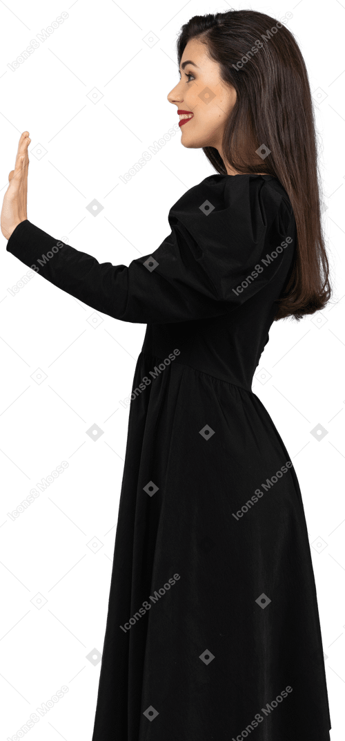 Вид сбоку улыбающейся приветствующей молодой леди в черном платье