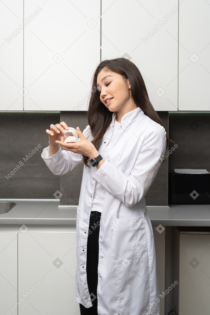 Three-quarter view of a young female dentist analyzing jaws prototype