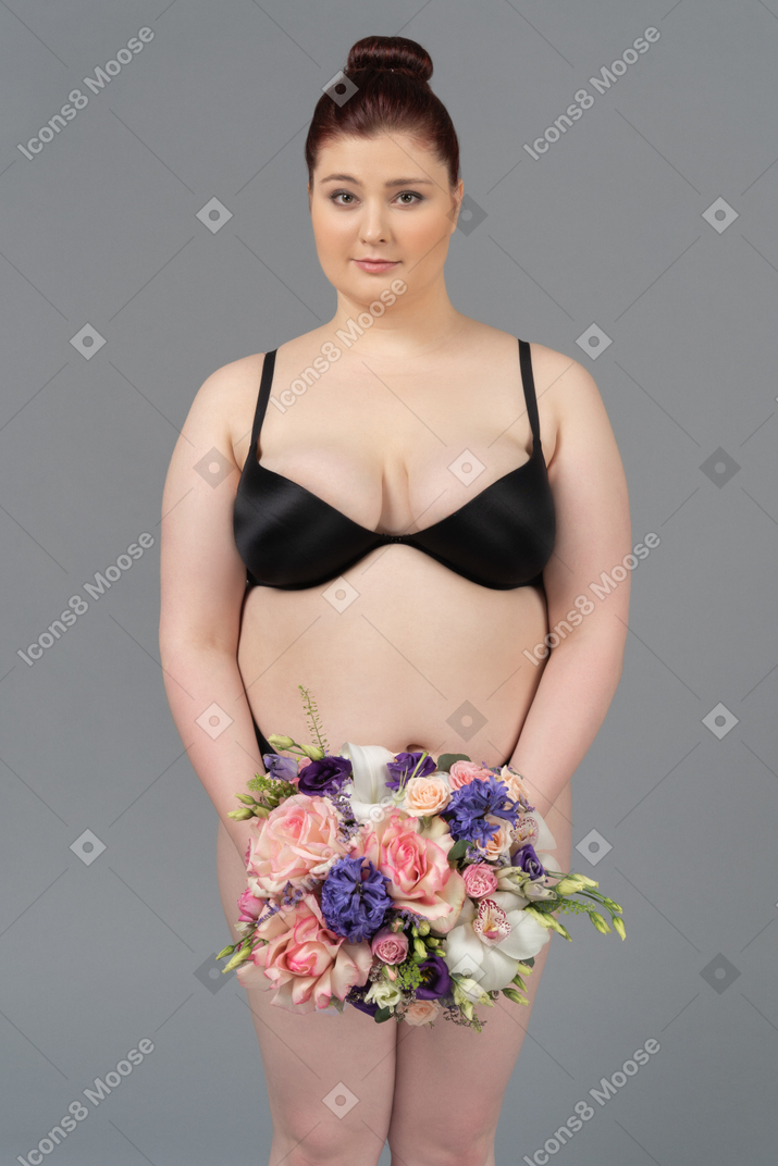 Linda mujer de talla grande posando con un ramo de flores
