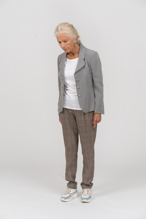 Vista frontal de una anciana en traje mirando hacia abajo