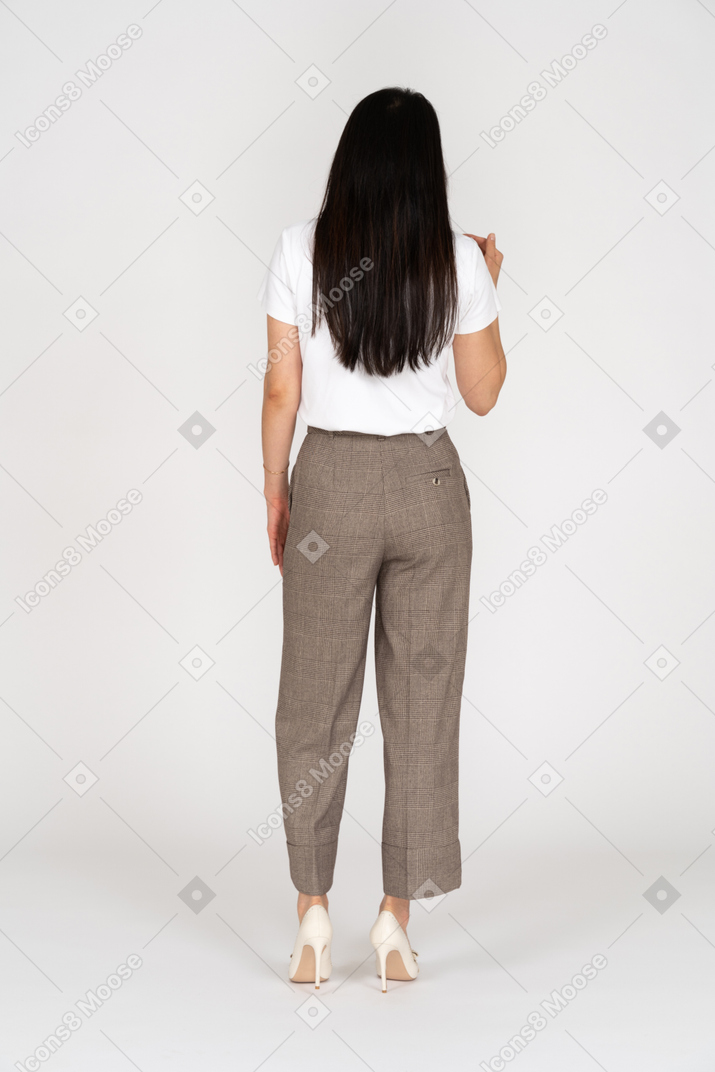 Vista de trás de uma jovem de calça e camiseta levantando a mão