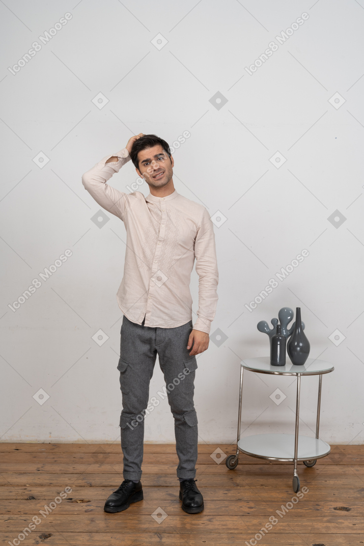Vorderansicht eines mannes in freizeitkleidung, der mit der hand hinter dem kopf steht