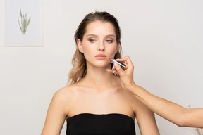 Front view of a make-up artist applying lipstick for a female model