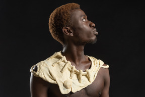 Retrato lateral de un hombre africano en el fondo oscuro con un collar de masa