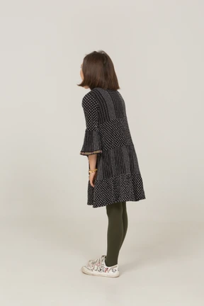 Three-quarter back view of a little girl in dress leaning forward