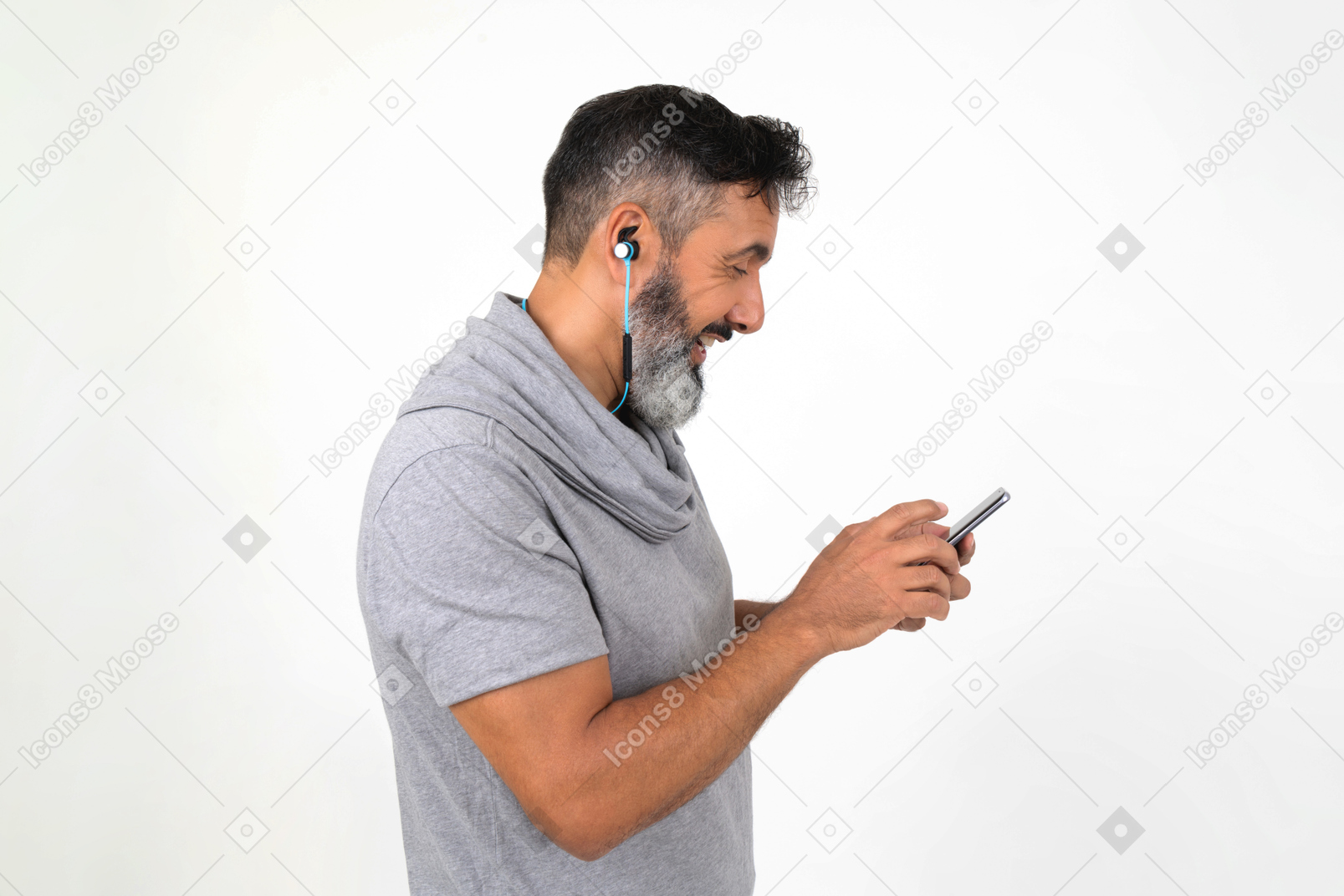 Smiling mature man listening to some music and using his smartphone