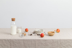 Bottle of milk, glass og milk, red apples and bowls