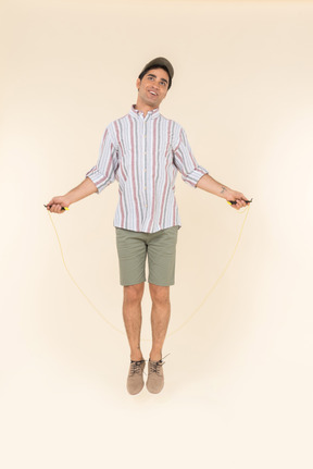 Excited looking young caucasian man jumping over jump rope