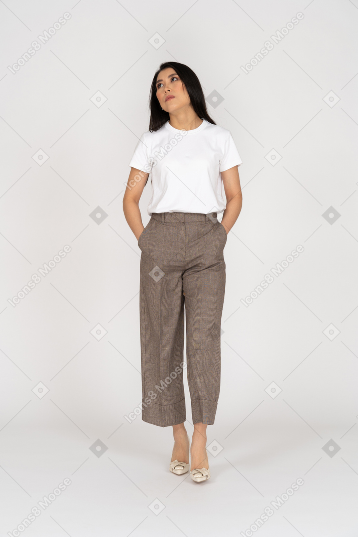 Front view of a walking bored young lady in breeches and t-shirt putting hands in pockets