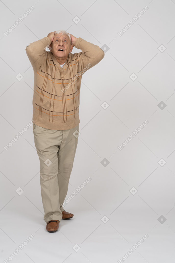 Vue de face d'un vieil homme impressionné debout avec les mains derrière la tête