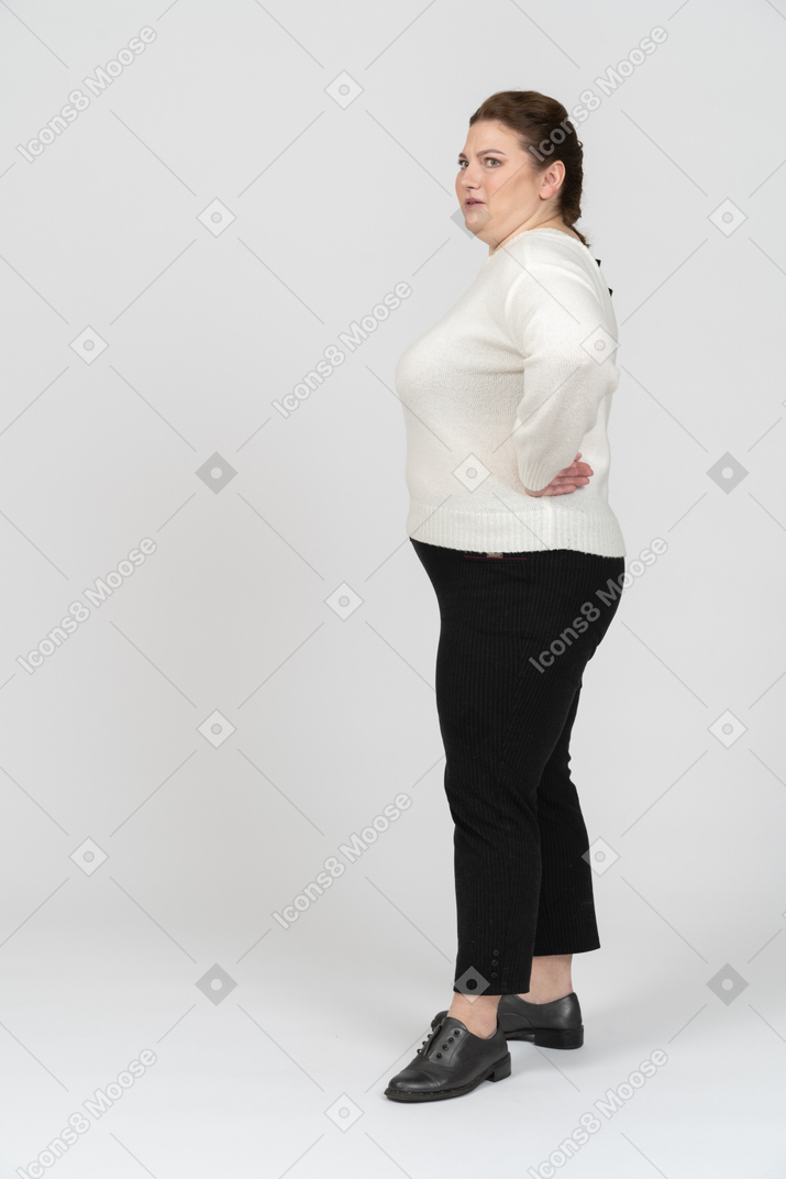 站立用在臀部的手的便服的肥满妇女