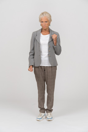 Vista frontale di una vecchia donna in abito che mostra il pugno