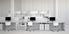 Белое офисное пространство с настольными компьютерами и офисными стульями