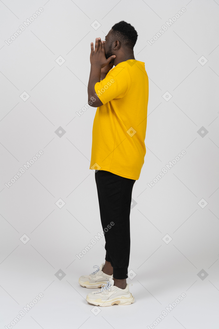 Side view of a screaming young dark-skinned man in yellow t-shirt