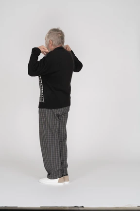 Elderly man standing with his hands on his shoulders