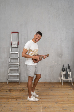 Vista lateral de um homem tocando cavaquinho e sorrindo