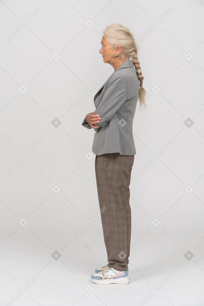 Side view of an old lady in grey jacket posing with crossed arms