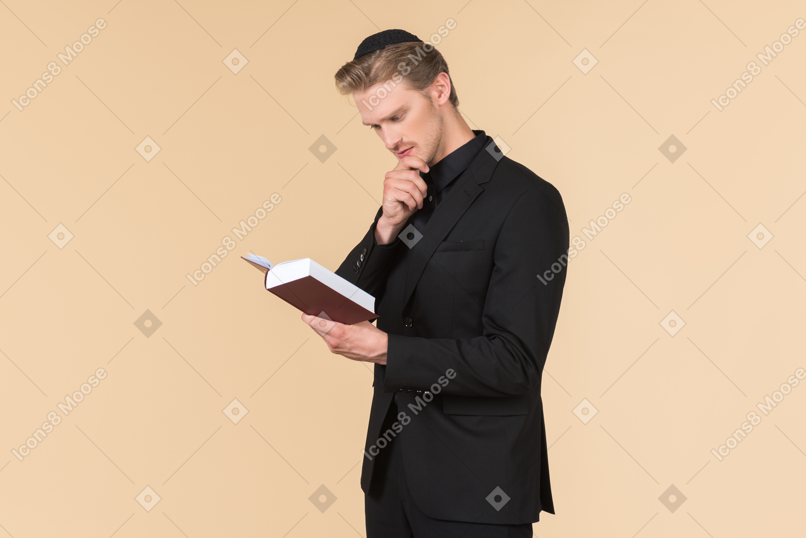 Young man in a black suit and a kippah reading a torah he's holding