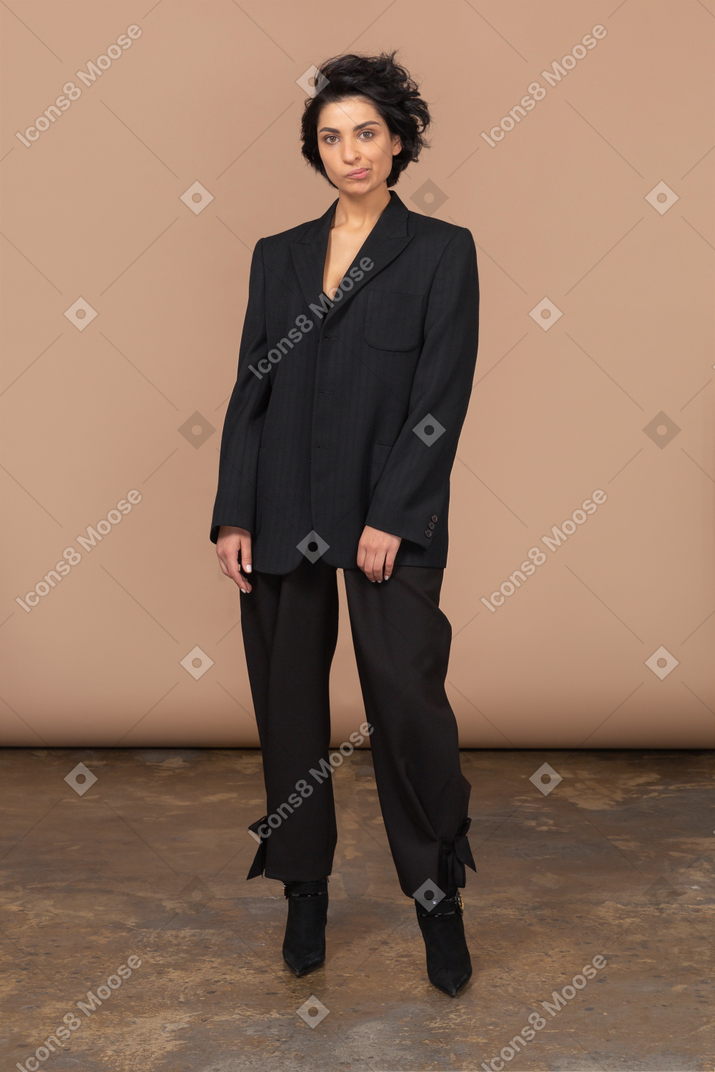 Вид спереди гримасничающей бизнесвумен в черном костюме, смотрящей в камеру