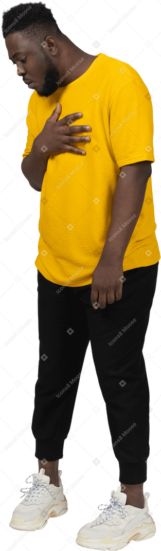 Three-quarter view of a surprised young dark-skinned man in yellow t-shirt touching chest