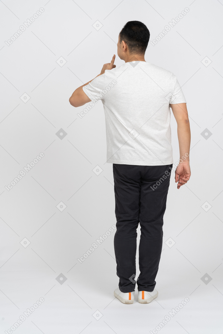 Back view of a man in casual clothes making hush gesture