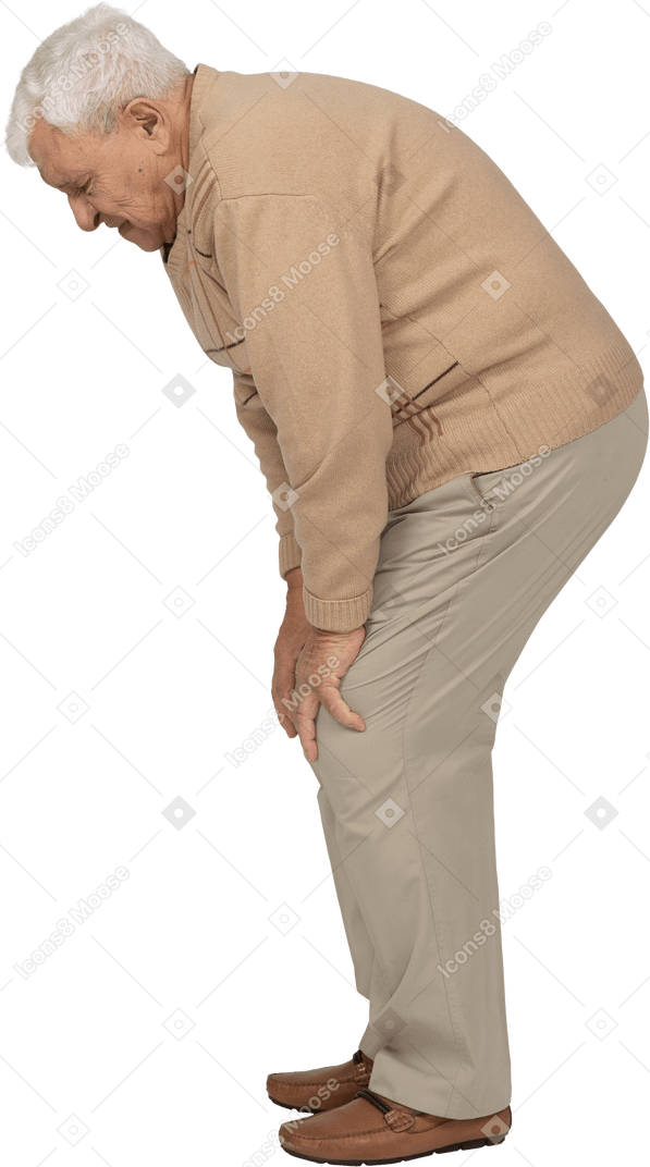 Seitenansicht eines alten mannes in freizeitkleidung, der sich nach unten beugt und sein schmerzendes knie berührt