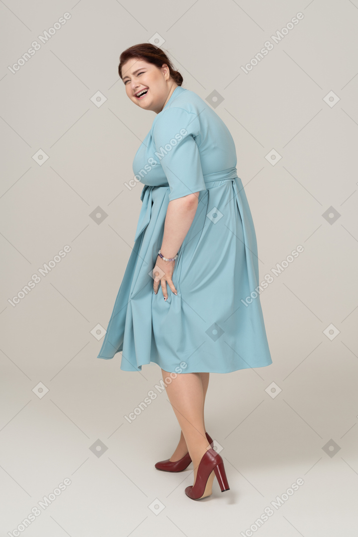 Женщина в синем платье позирует в профиль