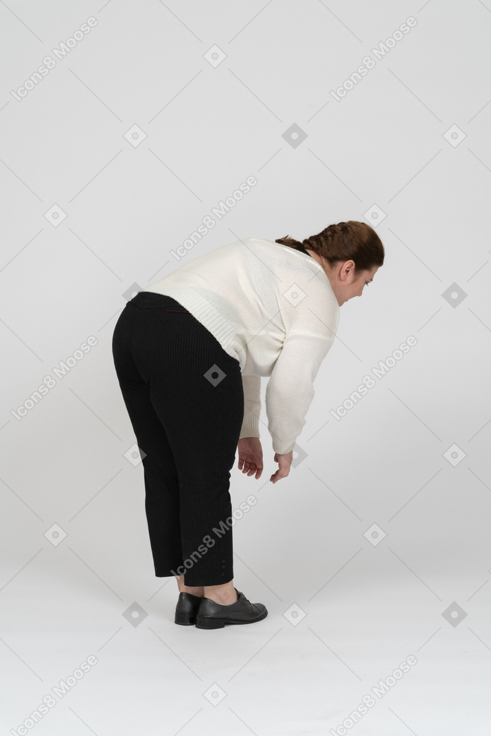 Side view of a plus size woman in casual clothes bending down
