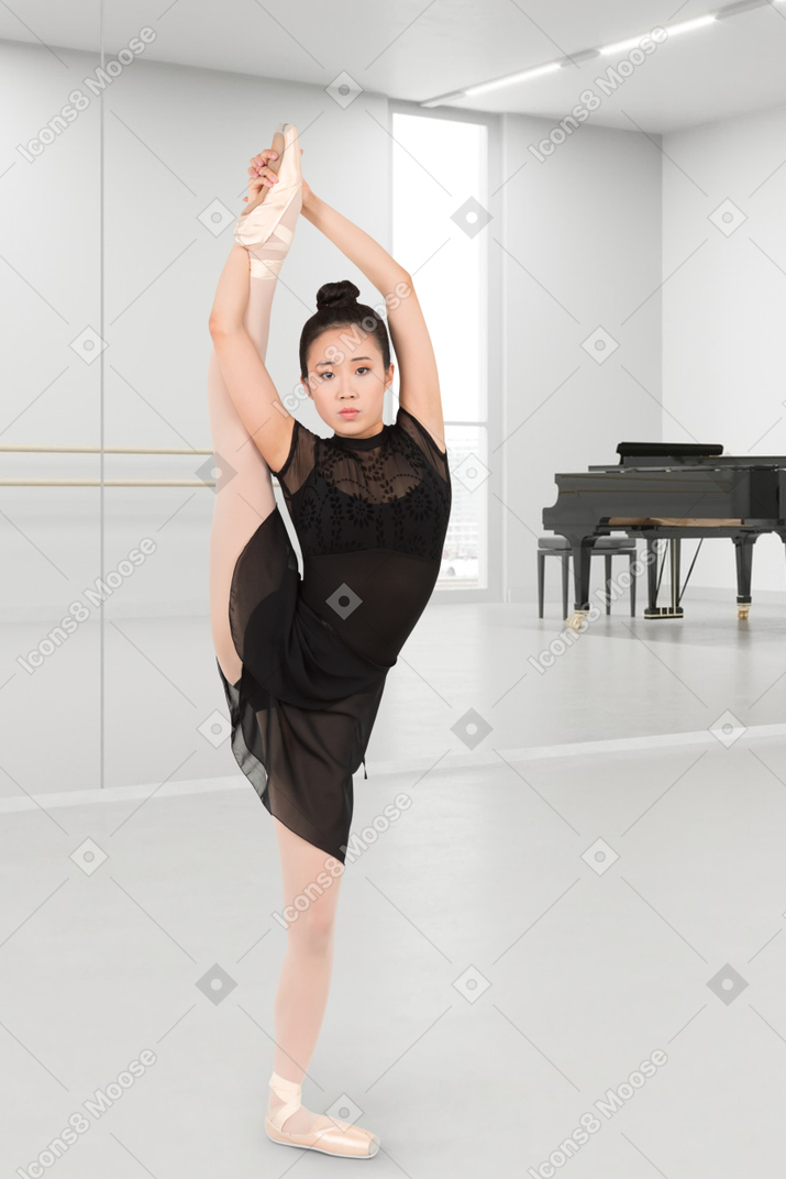 A woman in a black dress is doing a ballet pose