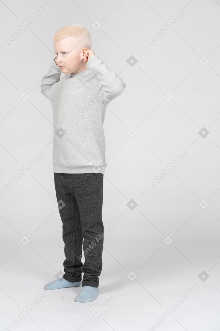 Side view of a little boy pulling his ears