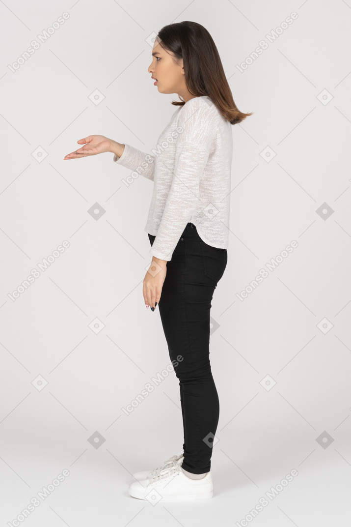 Vue latérale d'une jeune femme indienne en question dans des vêtements décontractés levant la main