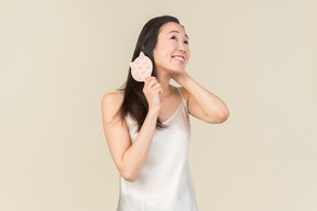 Smiling young asian woman brushing hair