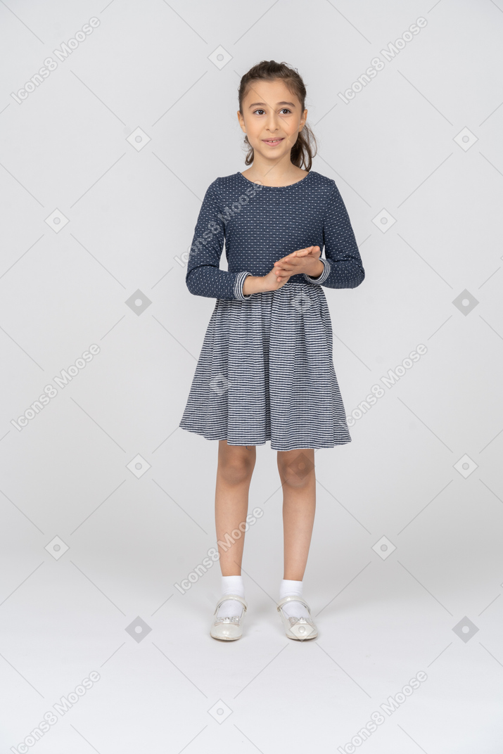 Vista frontal de una niña frotándose las manos y sonriendo