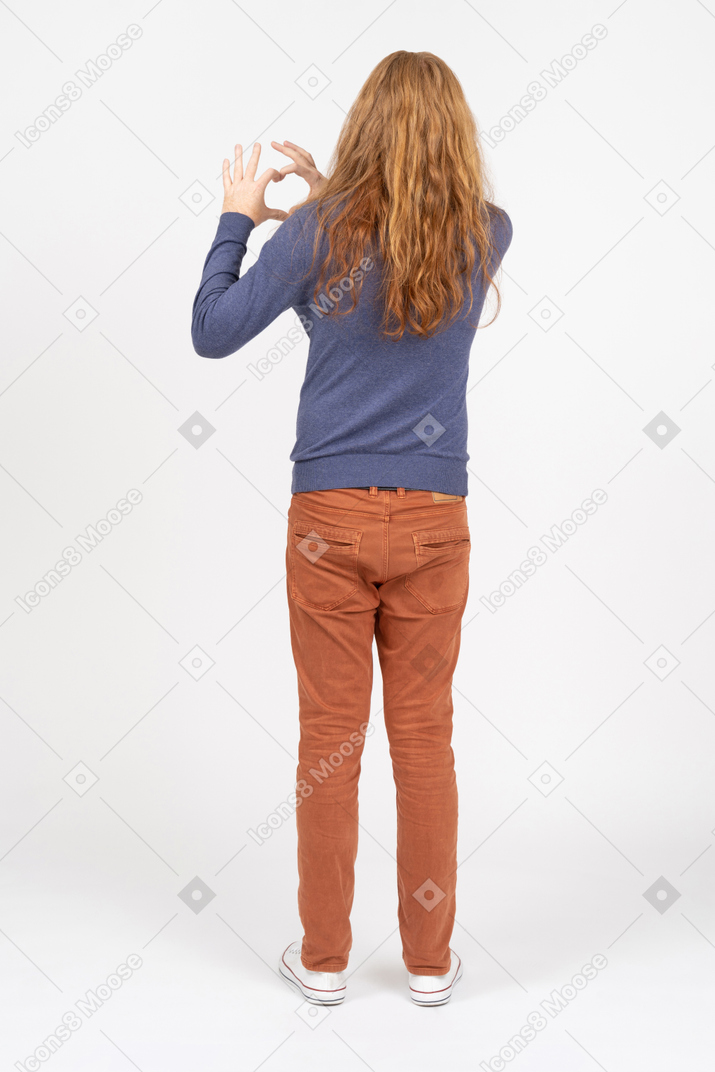 Vista traseira de um jovem em roupas casuais fazendo coração com os dedos