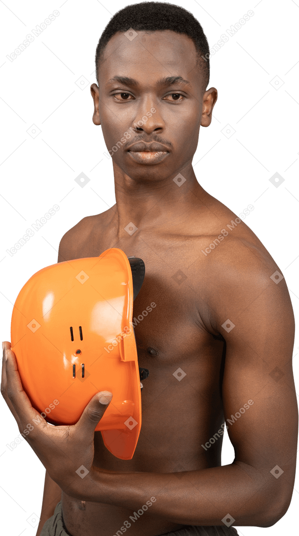 A shirtless young man holding a safety helmet