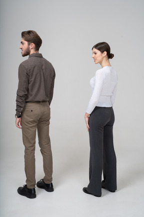 Three-quarter back view of a young couple in office clothing clenching teeth