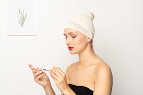 Young woman with bandaged head holding syringe